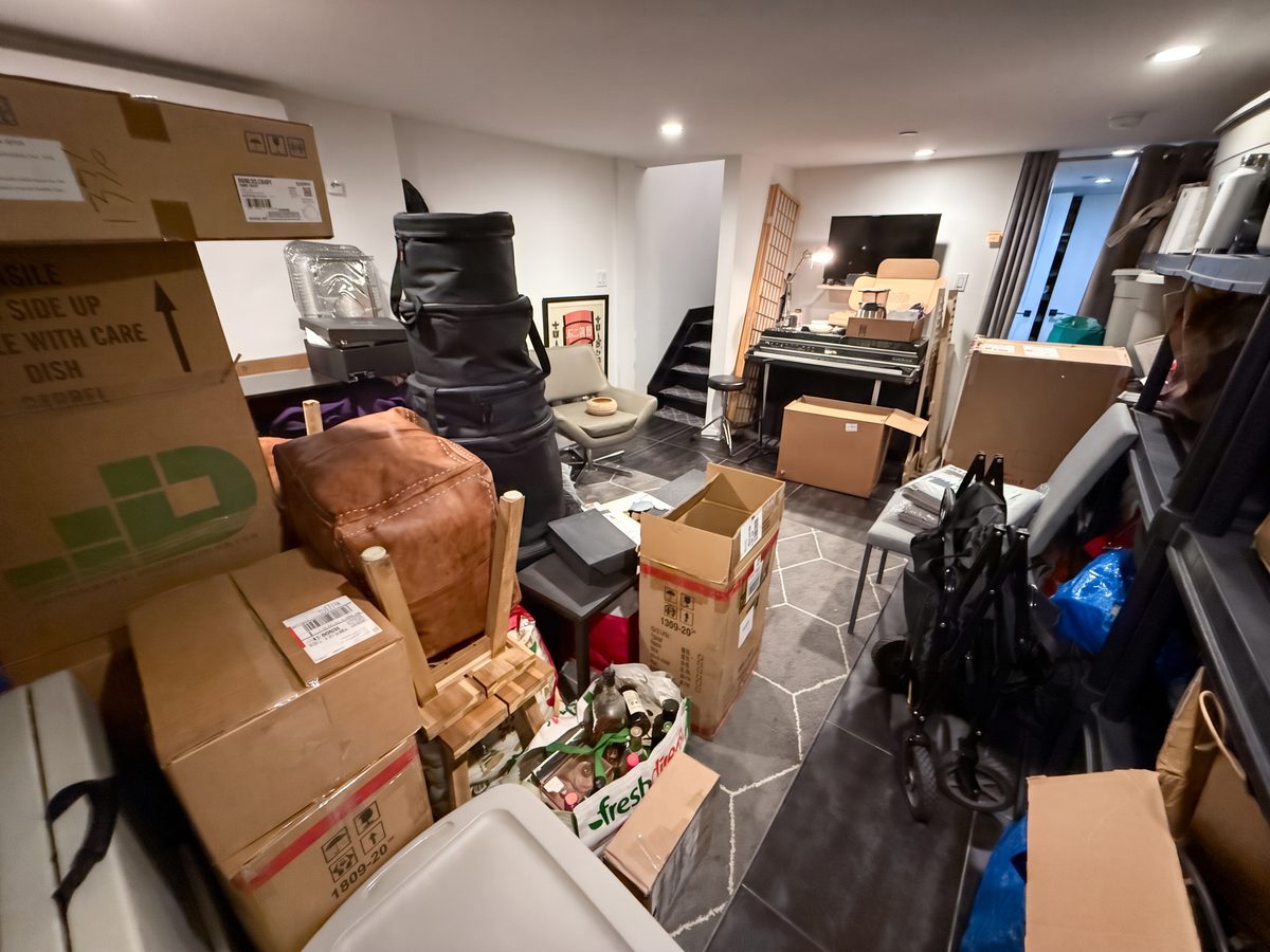 Basement before organizing, packed with moving boxes and cases blocking the walkway